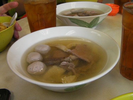 bowl of broth and several types of beef meat