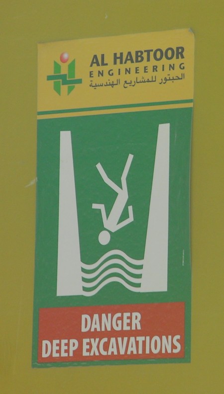warning sign showing figure falling into a deep hole