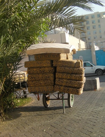 Moving 2 furniture cushions piled high on a hand cart
