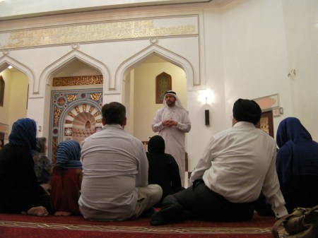 people sitting on the floor inside a mosque