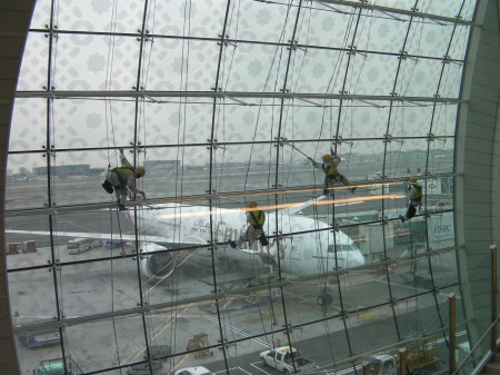 Airport window washers four mean using climbing equipment to clean large airport windows