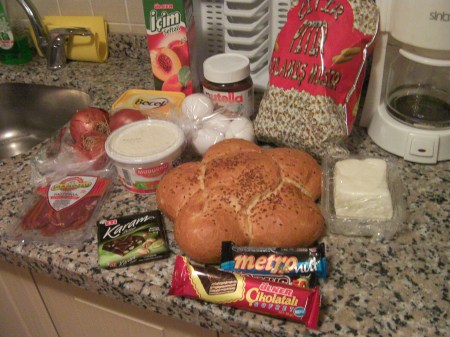 Groceries bread, butter, cheese, 4 candybars, onions, eggs, yogurt, juice, pistrami, popcorn