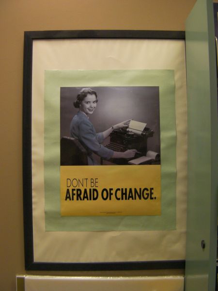 framed poster showing a black and white photo of a woman using a typewriter with the caption "don't be afraid of change"