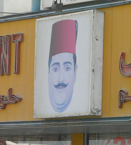 sign showing a man's head wearing a fez hat
