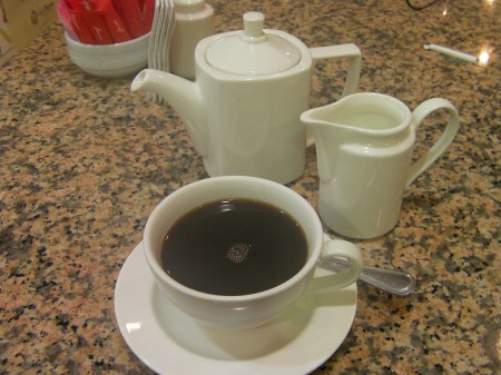 coffee pot, cream pitcher and coffee cup full of very dark coffee