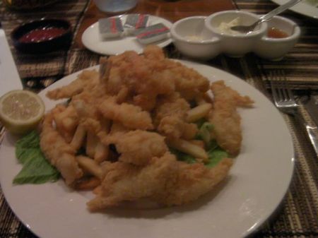plate piled with french fries and batter fried seafood