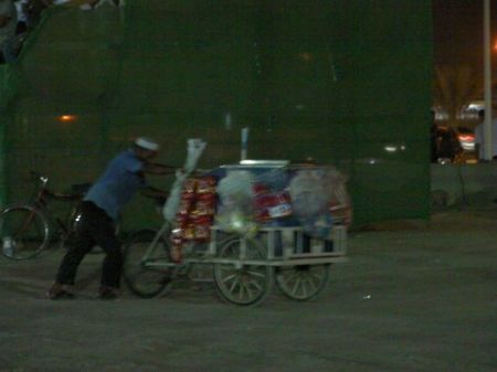a man with a bicycle cart loaded with snack foods