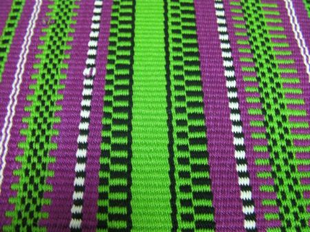 close up of magenta/green/white/black woven table runner