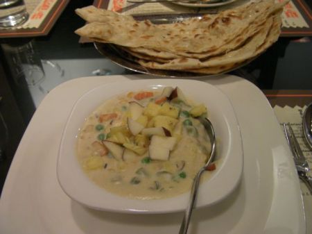 Korma bowl of veggies in creamy sauce topped with fruit
