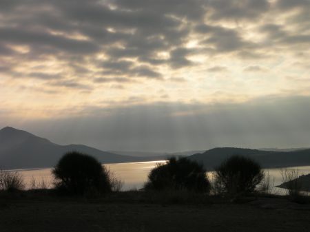 Sun shining through clouds over a lake