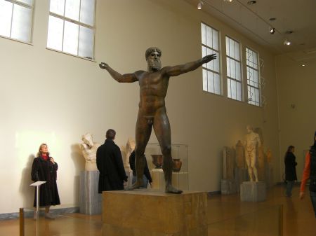large bronze sculpture of Zeus posed as if he is throwing a lightning bolt