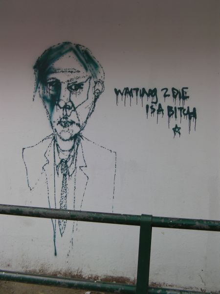 graffiti of a man in a suit with caption waiting to die is a bitch