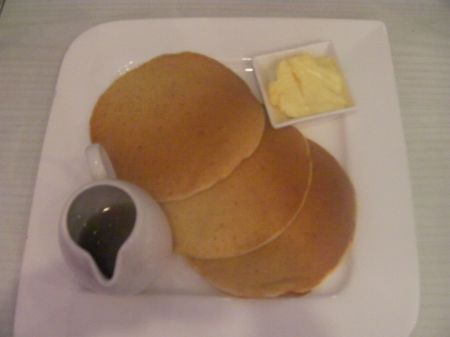 three pancakes, pitcher of syrup and butter