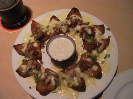 potato skins appetizer with cheese, bacon bits, and dip