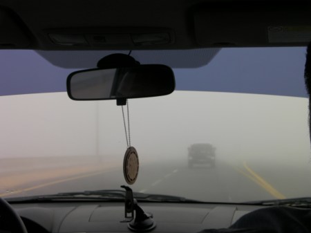 view through the car windshield showing another vehicle a few car lengths ahead which is barely visible