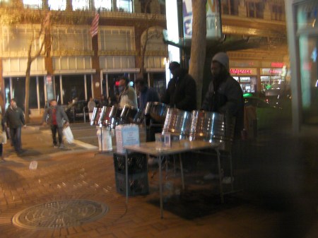 4 men playing steel drums on a street corner