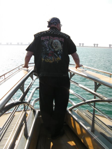 man wearing an Iron Maiden jacket standing at the bow of the boat