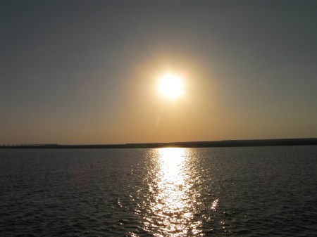 sun approaching the horizon, shining on the water
