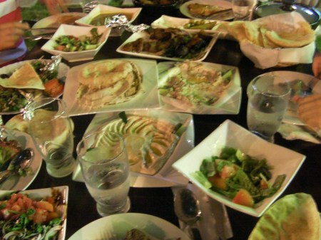 table full of dishes with hummus, bread, and meat