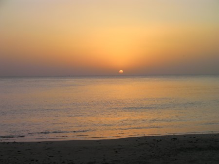 ocean, orange haze, half the sun showing