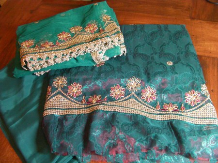 teal fabric with gold and red embroidery in the shape of flowers