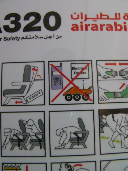 close up of the airplane safety guide sheet showing a red X through a remote control toy car
