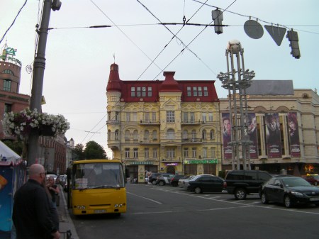 yellow building with a red roof, yellow bus, city street