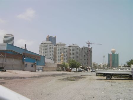skyscrapers in distance, unpaved road and old industrial shops in foreground