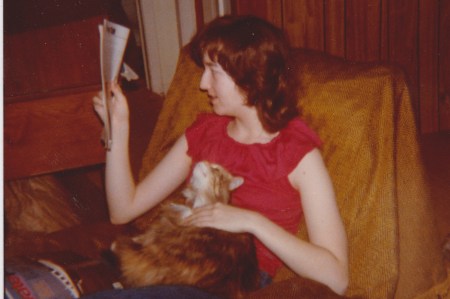 teen sitting with long haired calico cat in lap while reading
