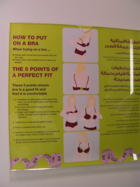 bilingual sign explaining how to put on a bra