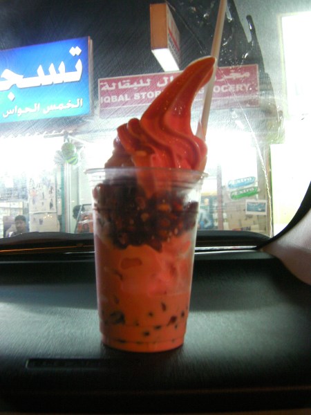 plastic glass of white and pink soft serve ice cream layered with pomegranate seeds