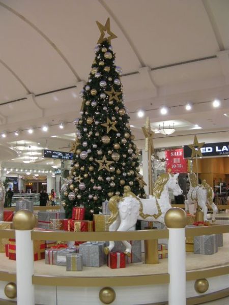 Christmas tree decorated in gold and silver surrounded by carousel horses