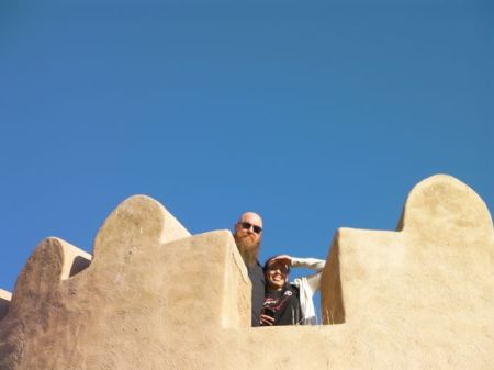 two people at the top of the fort tower seen between the crenallations