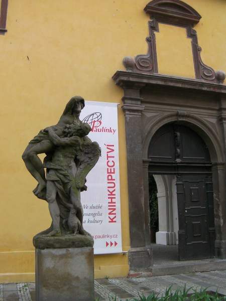 statue of a winged man holding a woman with an owl at his feet.