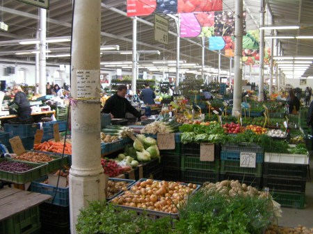 large warehouse room full of booths selling vegetables and fruit
