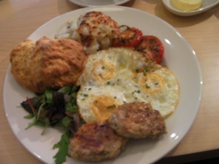 plate of eggs, sausage patties, potatoes, and a biscuit