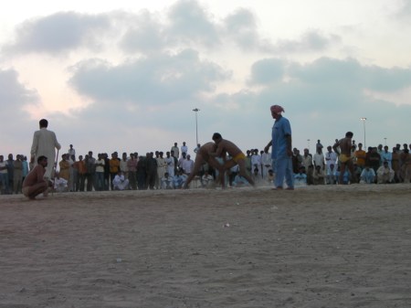 men wrestling in a sand lot