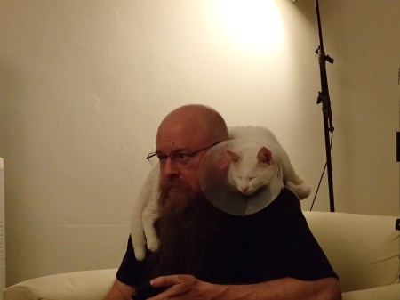 man with white cat laying on his shoulders