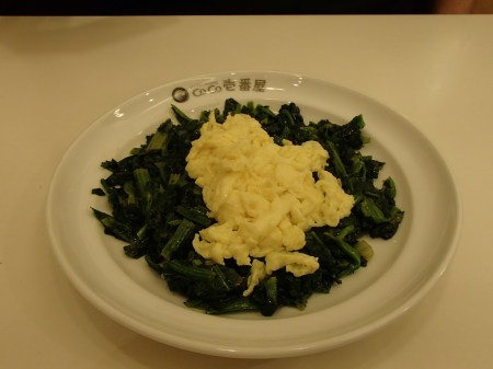 plate of cooked spinach topped with scrambled egg