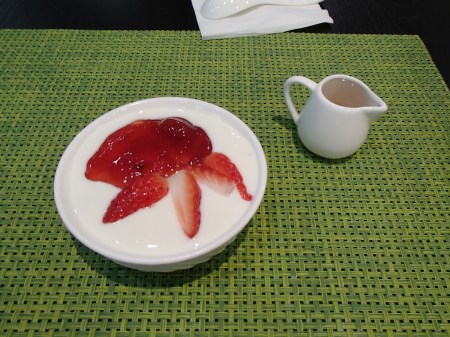 bowl of yogurt with strawberry syrup and strawberries on top