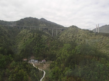 small farming community nestled among mountains with a modern highway above