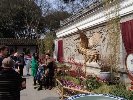 Garden entrance with people posing in front of bamboo crane sculptures