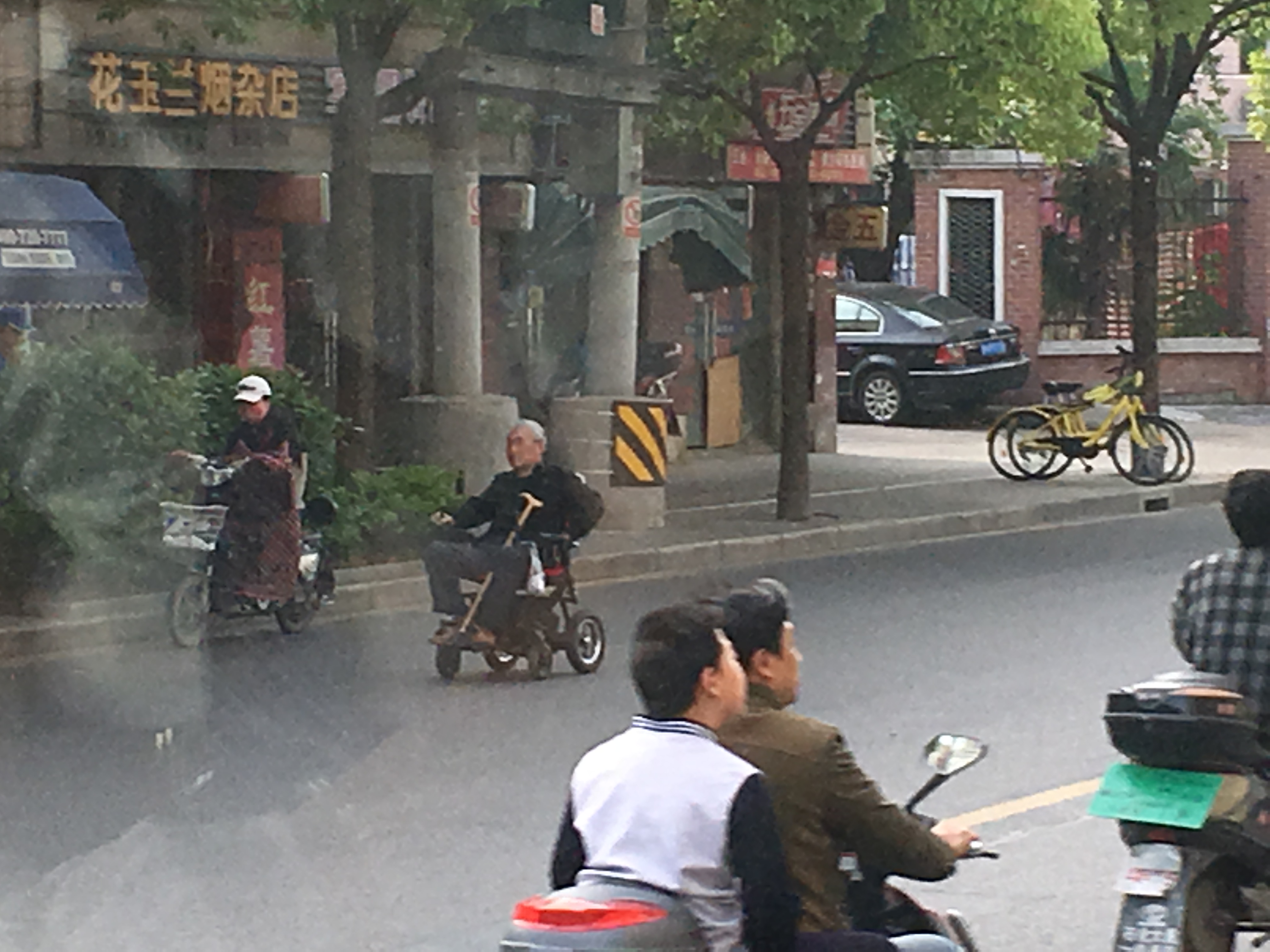 an elderly man in an electric wheelchair traveling down the street
