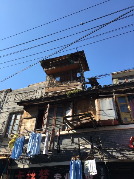 old building with ramshackle pigeon coops on the roof and laundry hanging from the second story