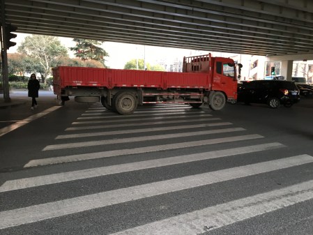 a large red truck blocking a very wide crosswalk