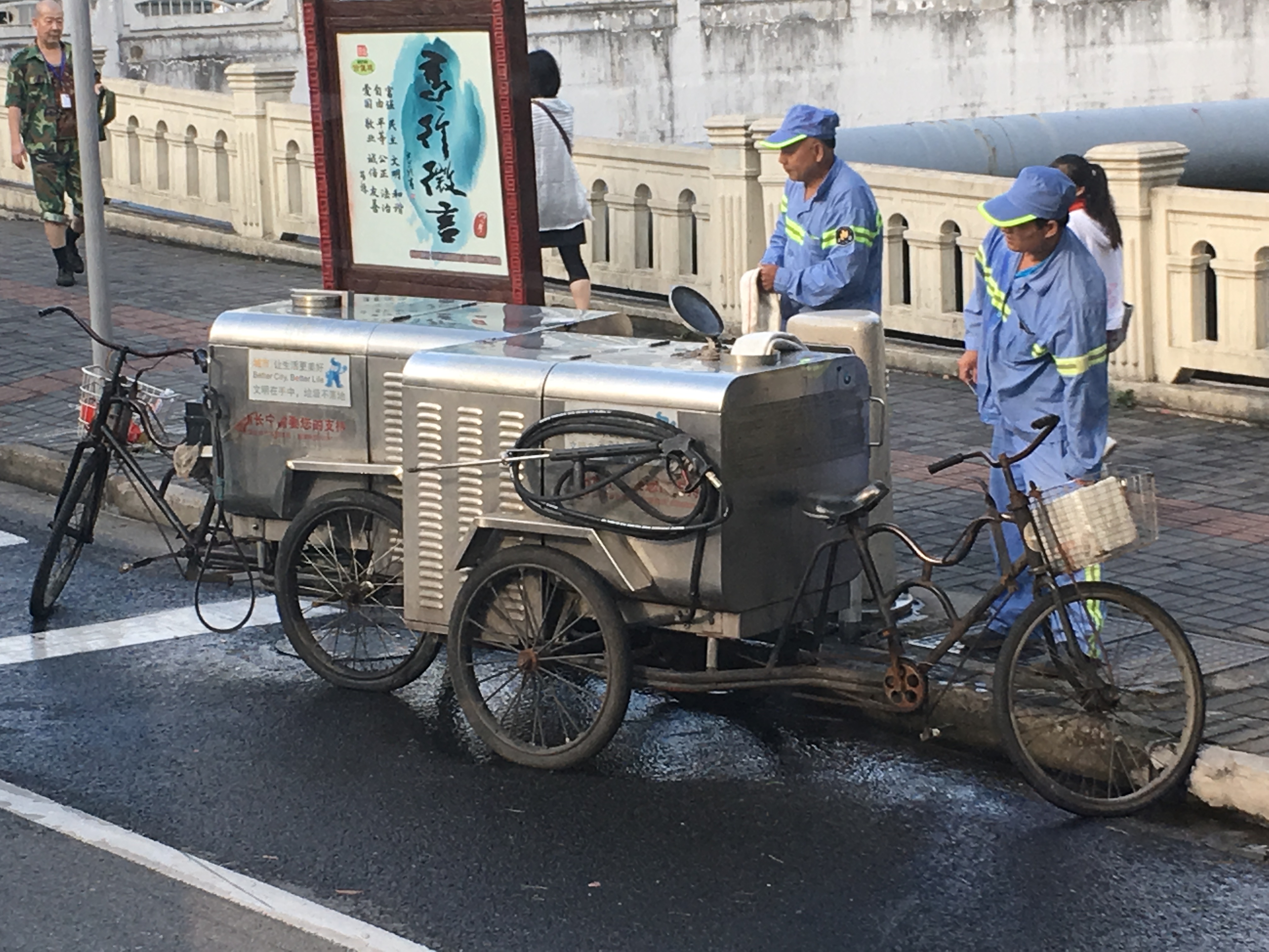 street washers filling up the tanks on their three wheeled bicycle street washing machines