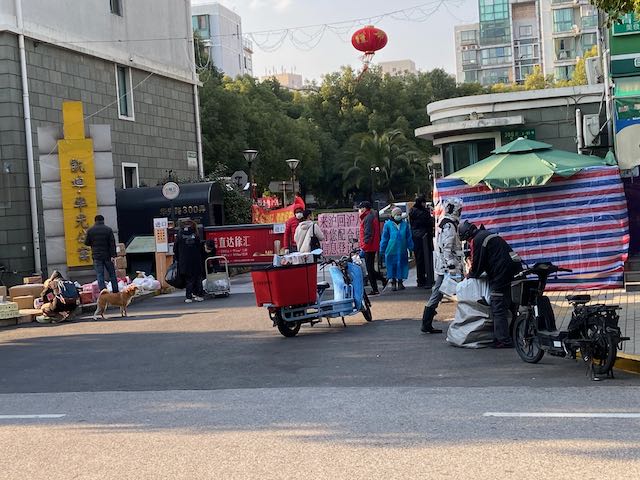 apartment gate area where several people are leaving or receiving deliveries.