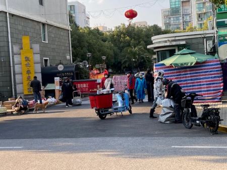 apartment gate area where several people are leaving or receiving deliveries.