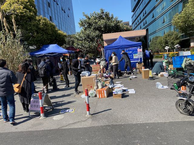 temporary tents at a business gate, piles of boxes dropped off by delivery personnel