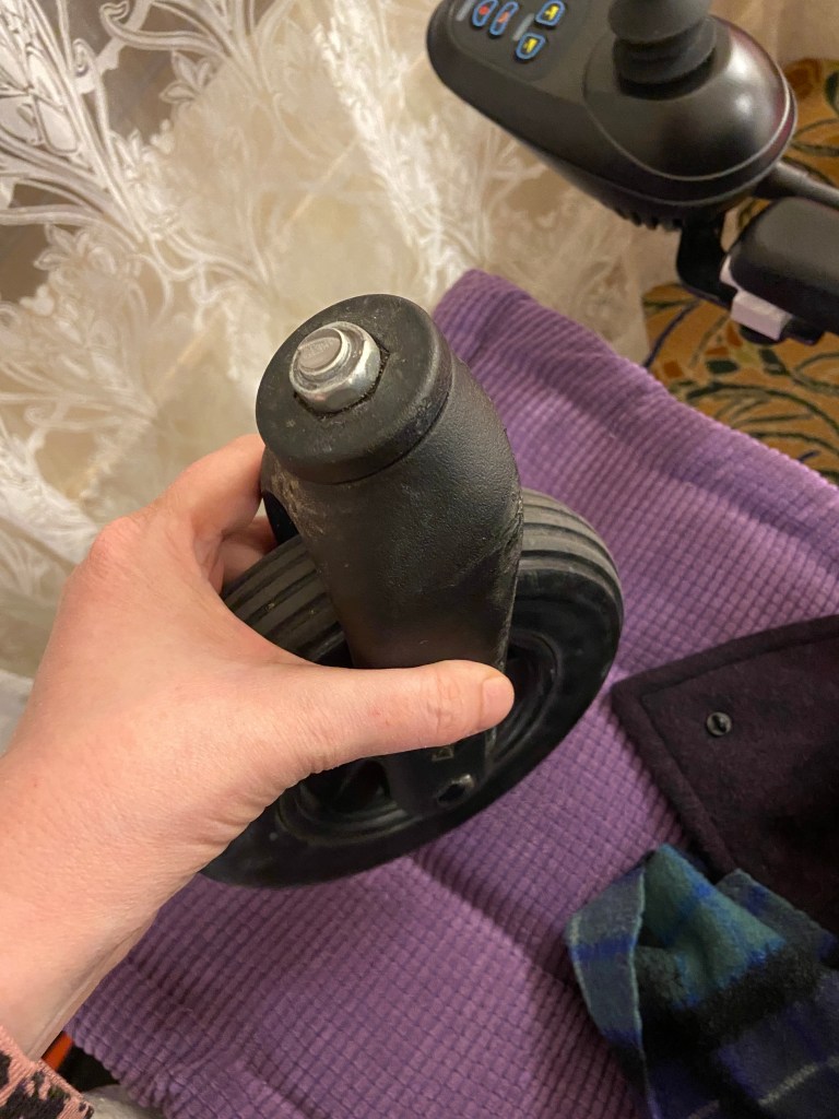 hand holding a wheelchair wheel showing the broken metal post 